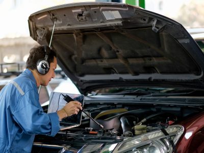 Asian automotive mechanic with blue uniform use electronic tools to check the car