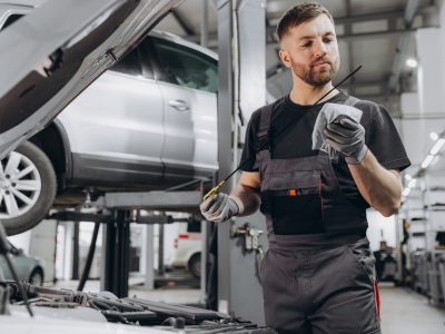 Car mechanic checking the engine oil level in the service center